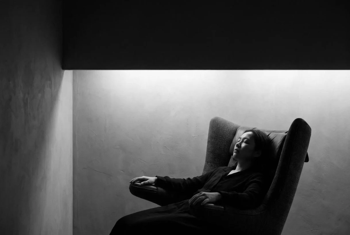Pessoa reclinada em um ambiente de recuperação com iluminação suave.